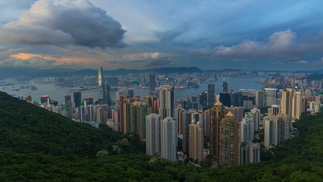 Time lapse movie of clouds and blue sky over densely populated city of Hong Kong and Victoria Peak Harbor at Sunset into blue hour 4k UHD movie