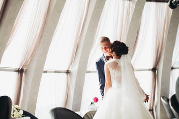 Naklejka premium Happy wedding couple, bride and groom posing in hotel