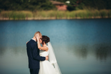 Love and passion - kiss of married young wedding couple near lake