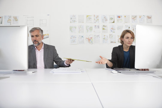 Two indifferent colleagues at their desks in an office