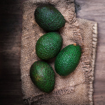 Fresh avocado on cutting board over wooden background..