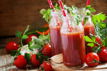 Smoothies of tomatoes and spices in glass bottles with festive r