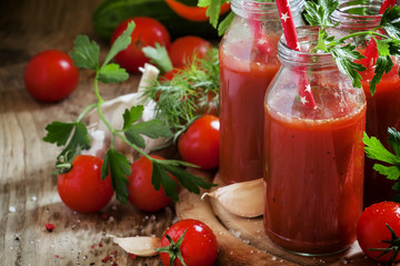 Smoothies of tomatoes and spices in glass bottles with festive r