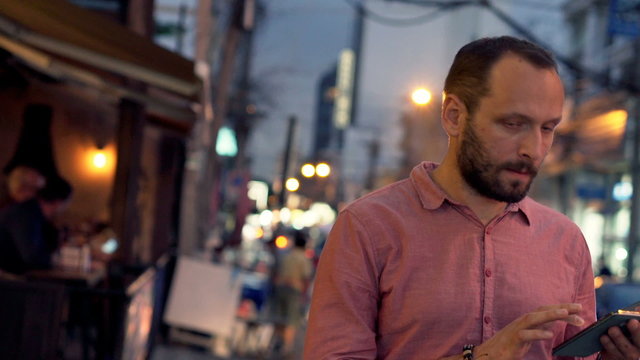 Lost man checking map on smartphone in city at night
