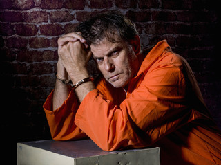 Mature man, handcuffed and locked in prison, with gestures of repentance