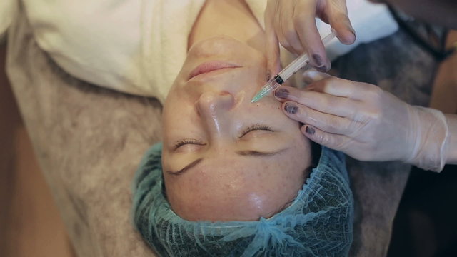 A woman is getting a mesotherapy of her face
