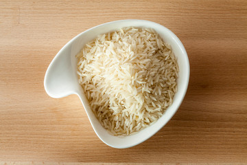 Riso Basmati in ciotola bianca su sfondo di legno