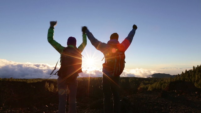 Success, achievement and accomplishment concept with hiking people cheering and celebrating of joy with arms raised outstretched up on trekking hike outside. Hikers having fun at sunset.