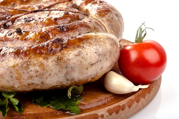 fried pork sausages on a wooden plate with cherry tomatoes and hot peppers