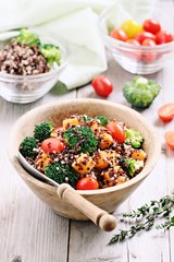 Quinoa salad with broccoli,sweet potatoes and tomatoes on a rustic wooden table.Superfoods concept.Selective focus. 