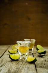 Gold tequila shots on rustic wood background