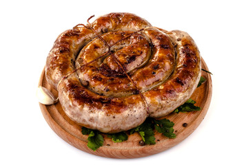 fried pork sausages on a barbecue on a wooden plate with cherry tomatoes and hot peppers