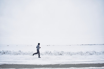 Fototapeta na wymiar The athlete runs in the winter on the road