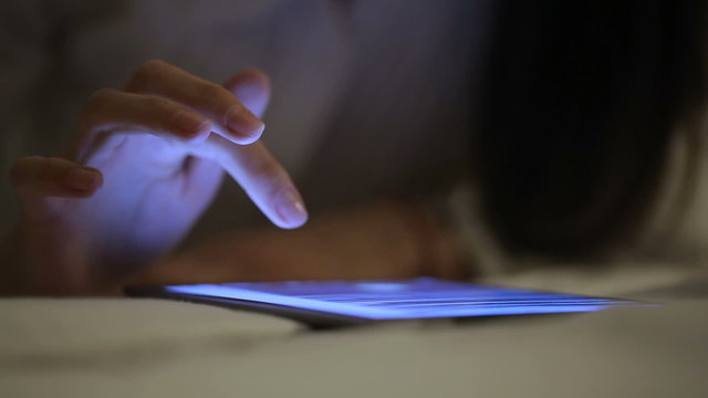 Woman finger touching tablet touchscreen at night time. Close upv