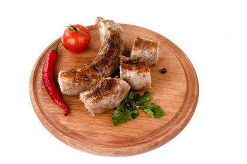 fried pork sausages on a wooden plate with cherry tomatoes and hot peppers