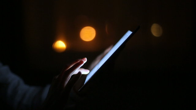 Woman finger touching tablet touchscreen at night time. Close upv