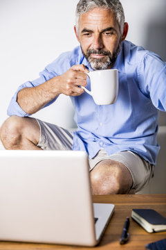Portrait of businessman having a coffee break at his home office