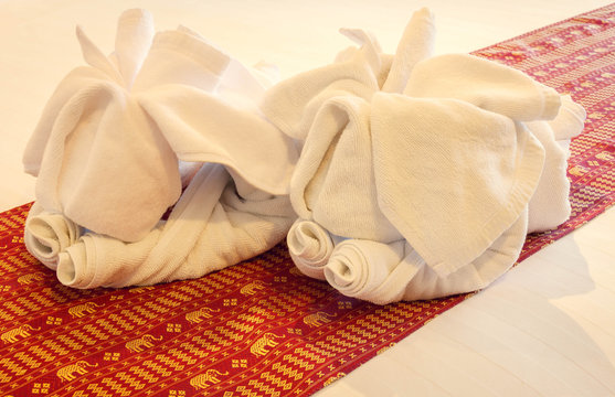 two white towel elephant,red mat on white cloth background.