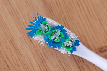 Close-up used colorful tooth-brush on the wooden background.