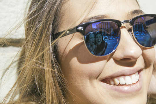 Friends of young woman reflecting at her sunglasses