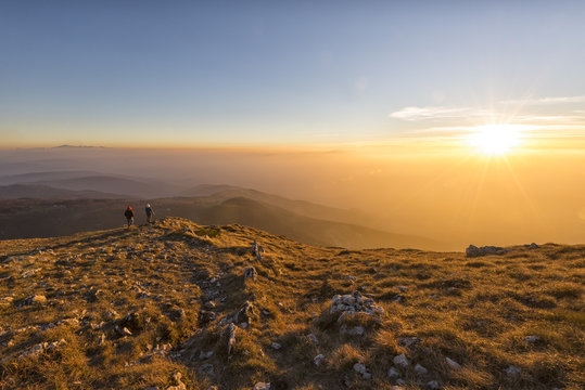 Italy, Marche, Monte San Vicino, two hikers looking at view at sunset
