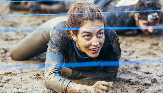 Participants in extreme obstacle race crawling under electric wire
