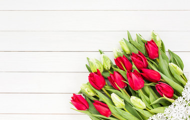 Red tulips bouquet decorated with lace on white wooden table. Copy space, top view