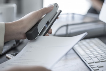 Close-up of woman at desk stapling a document