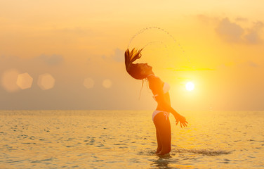 Girl jumping on the beach at sunset