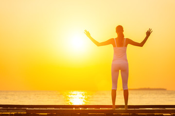 Fototapeta premium Young woman practicing yoga on the beach at sunset