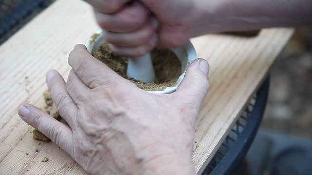 A man grinds oak galls to a powder to use as ink pigment.