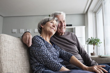 Happy senior couple sitting together on couch at living room