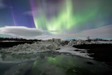 Fototapeta na wymiar Northern Lights above an iceberg in a lagoon