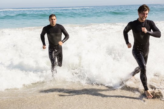 Handsome men running in wetsuits - Powered by Adobe