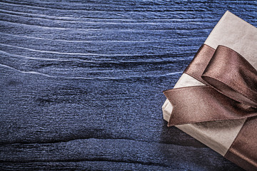 Gift box with brown satin ribbon on wooden board