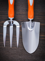 Hand spade and trowel fork with handles on vintage wood backgrou