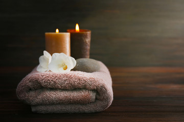 Fototapeta na wymiar Aroma candles, towel and beautiful flowers on wooden background