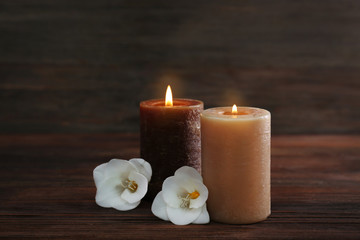 Obraz na płótnie Canvas Aroma candles and beautiful flowers on wooden background