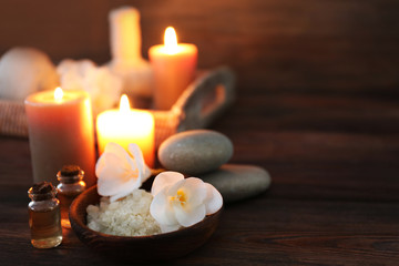 Spa composition with alight candles on wooden background in the dark