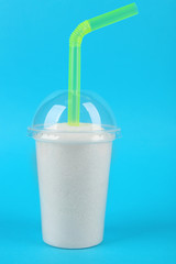 Plastic smoothie cup with granulated sugar and cocktail tube on blue background