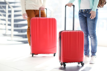 Couple waiting with large red suitcases, close up