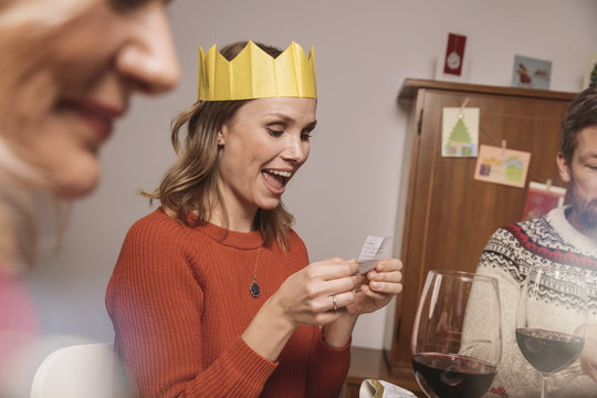 Woman with paper crown reading a poem from her Christmas cracker