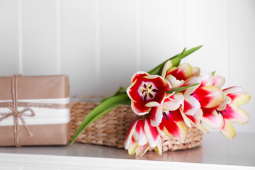 Bouquet of variegated tulips with gift box on white shelf