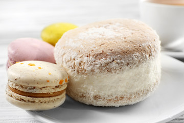 Delicious cake and macaroons on plate