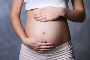 Fototapeta na wymiar Pregnant woman on grey wall background