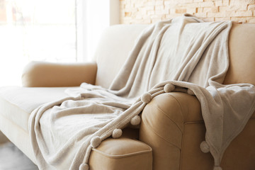 Gray blanket draped over a beige couch