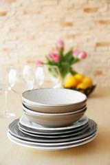 Stack of plates and bouquet of pink tulips on wooden table.