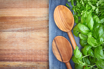 Basil, parsley and wooden spoons, culinary background