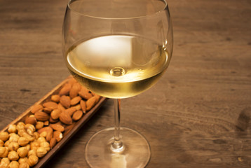 Glass of white wine and almond walnut on wood table