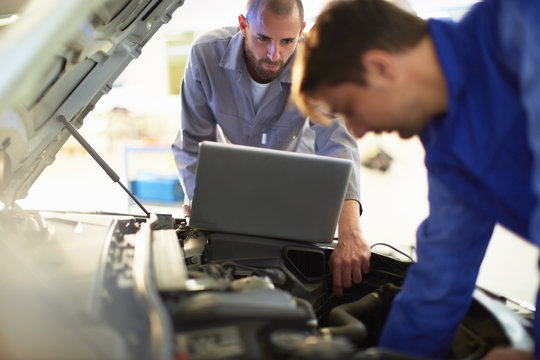 Two car mechanics at work in repair garage